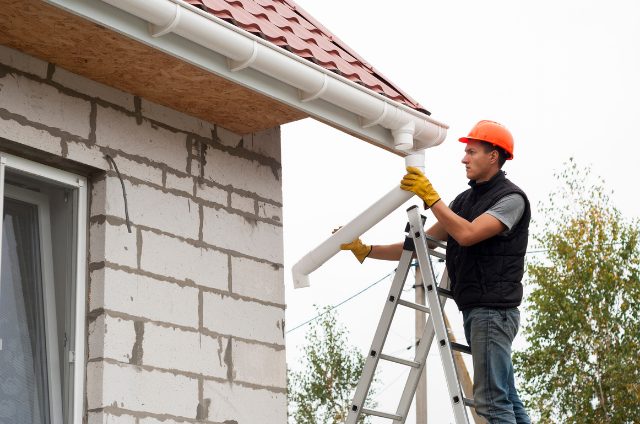 Worker installing Eugene Gutter standing on a ladder with safety hat on